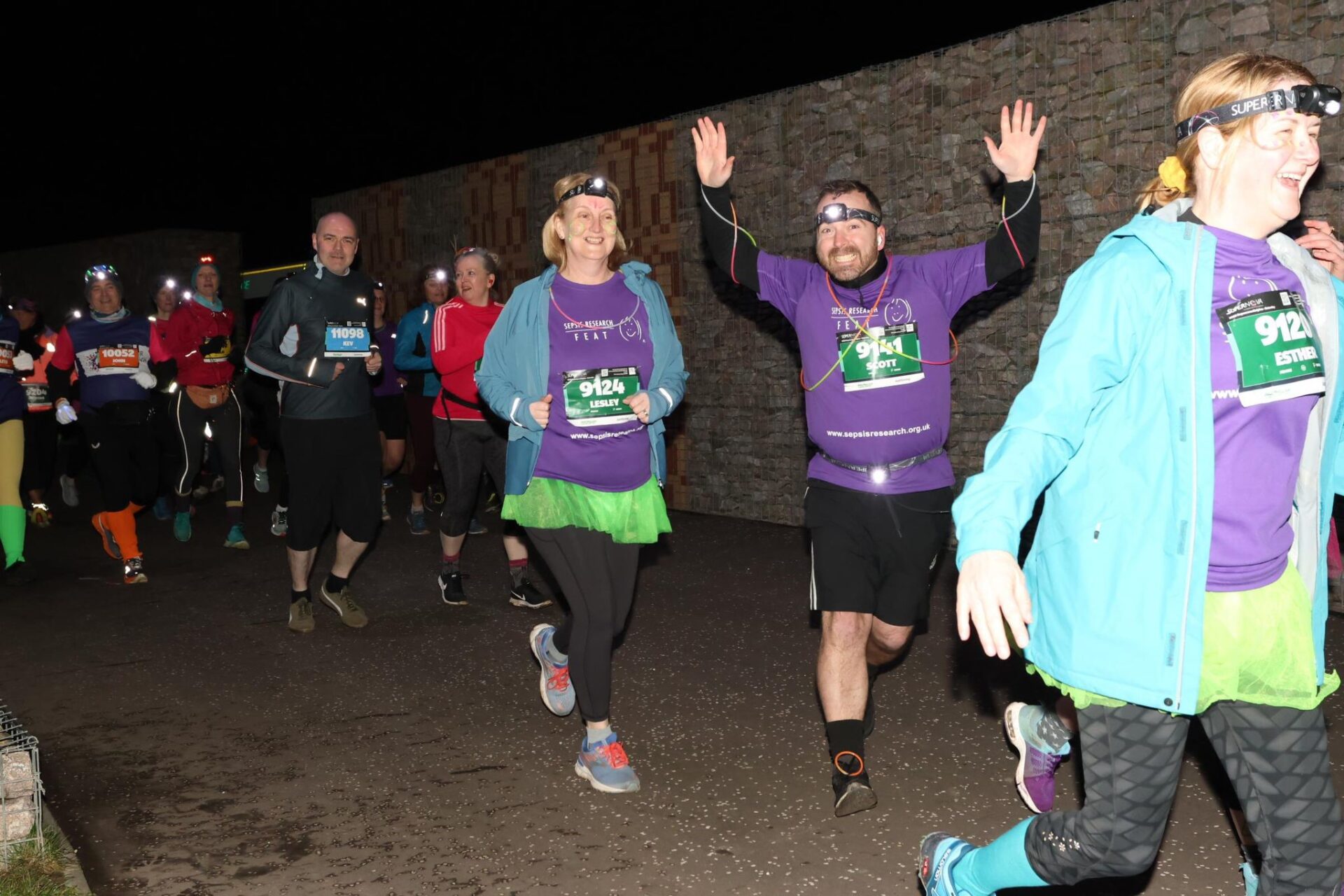 Runners are depicted running at night, wearing headlamps and purple "SEPSIS RESEARCH FEAT" shirts.