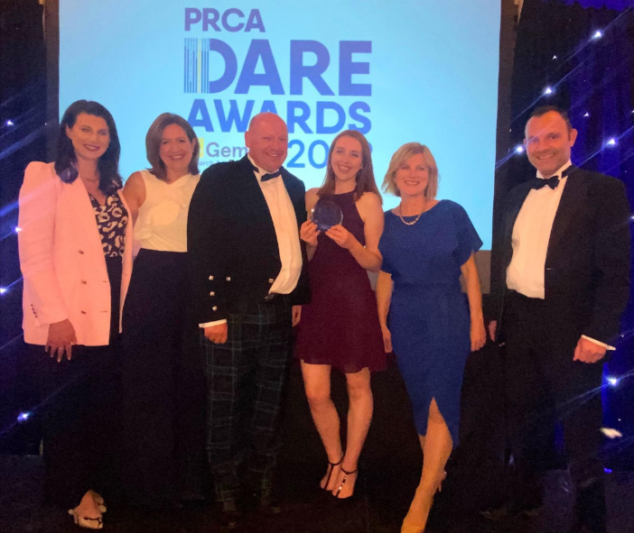 Six people pose with an award in front of a screen displaying "PRCA DARE AWARDS 2023."